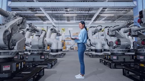 Woman Using Laptop in High-Tech Robotic Factory