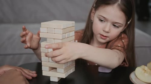Kleines Mädchen spielt Holzkonstrukteur am Tisch