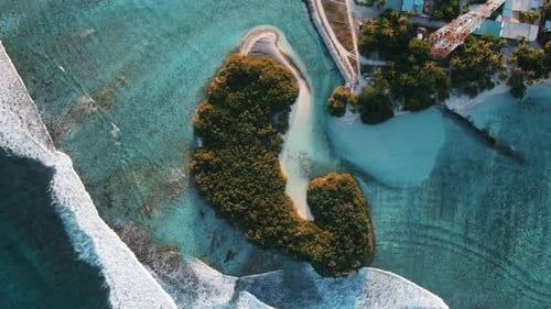 green island with white sand beach waves and blue lagoon