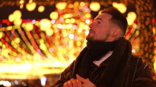 Front View Young Positive Caucasian Man Walking in Evening City on Christmas Night Waving Smiling