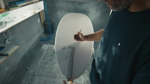 Surf factory. Adult male shaper creates the surfing board on the factory