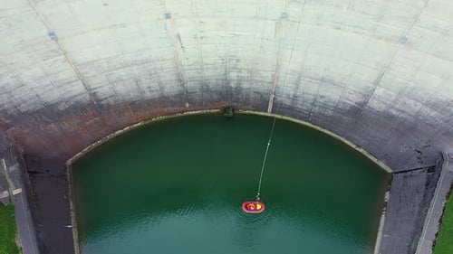 Aerial drone view of a person hanging on a bungee jumping cord rope to 50m high dam platform while a
