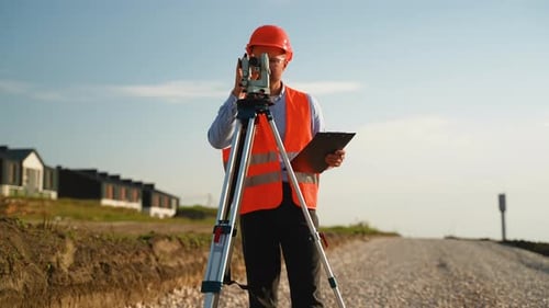 Surveyor Using Theodolite Inspecting Construction Site on Sunny Day