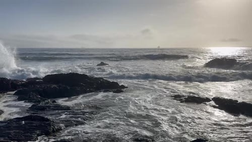 Dramatic Ocean Waves Crashing Against Dark Coastal Rocks At Sunset