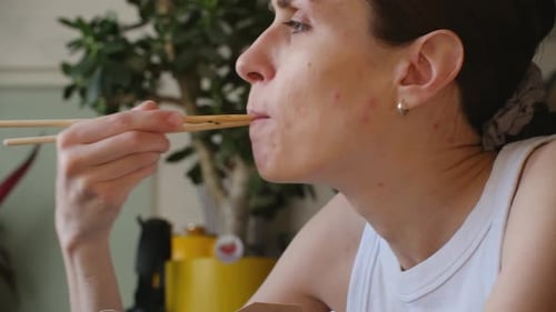 Woman Eating Noodles with Chopsticks Close Up Indoors