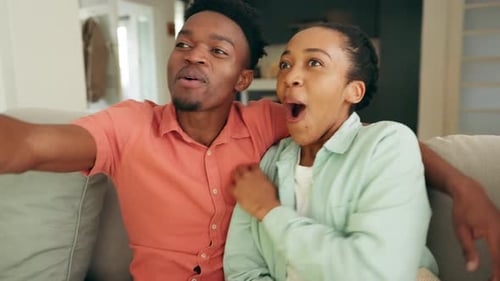 Excited Couple Watching Television Together at Home