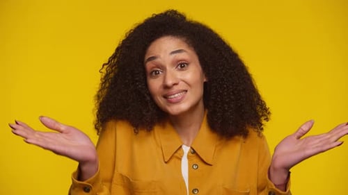 Young Woman Smiling with Hands Open on Yellow