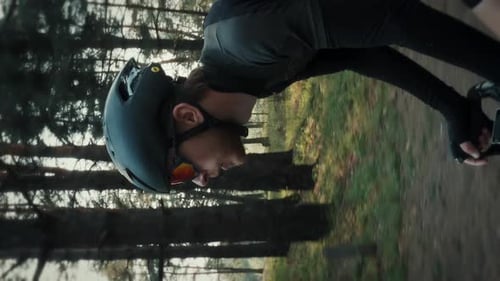 Male cyclist in sportswear rides bicycle in forest park. Vertical video