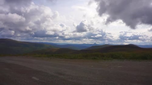 Vista panorâmica, dirigindo o topo da World Highway, com vista para colinas verdes e a selva de Yukon, em uma nuvem