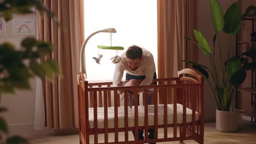 Father Holding Newborn Baby in Sunlit Nursery