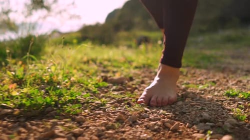 Free young woman walking barefoot through forest, sunrise peaceful nature walk
