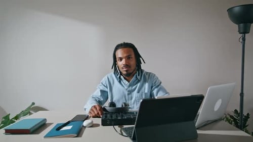 Young Adult Sits at Desk With Tech
