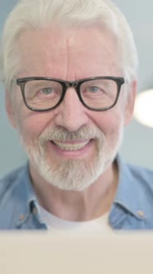 Close Up of Old Man Smiling at Camera while using Laptop, vertical video