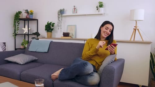 Young Woman Uses Smartphone in a Cozy Home