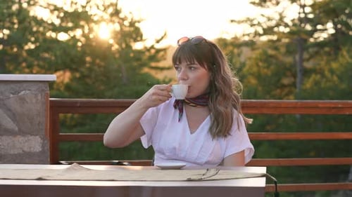 Woman Drinking Coffee In The Forest At Sunset