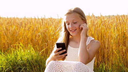 Teen Girl Using Phone in Golden Wheat Field