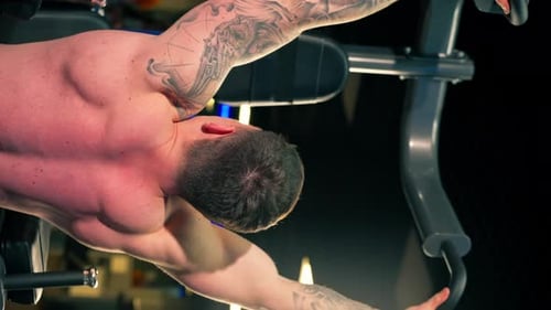 Vertical Video in the Gym Young Handsome Guy with Tattoos Doing Pullups on the Horizontal Bar