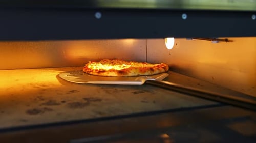 Pizza in oven. Baking pizza. The chef is turning hot pizza with a spatula in a stove.