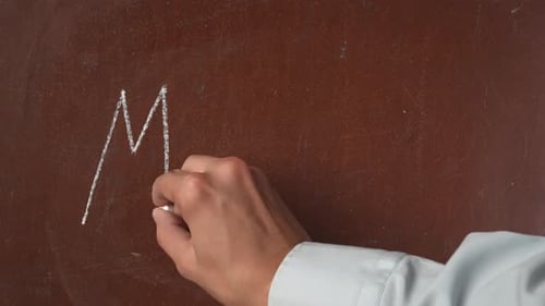 Textured Brown Chalkboard Background Male Hand Writing 'Menu' on the Board with a Piece of White