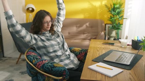 Woman Stretching and Working on Laptop at Home