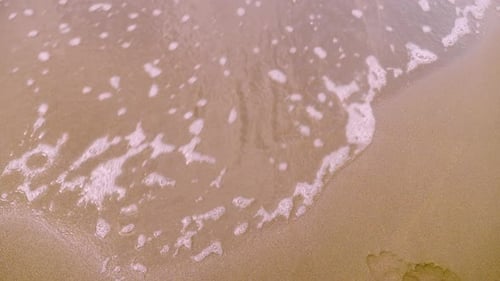 Onda de água lava a inscrição 2026 na areia. conceito de ano novo