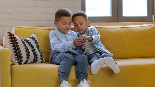 Young Boys Using Mobile Phone Together on Sofa