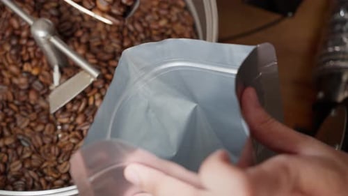 Scooping Roasted Coffee Beans into a Silver Bag