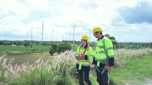 Ingenieur und Arbeiter besprechen das Projekt vor dem Hintergrund von Windkraftanlagen