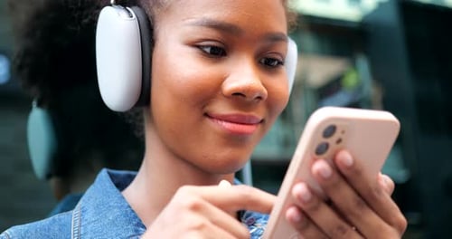 Young Woman Using Mobile Phone Wearing Headphones