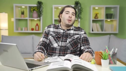 Young Man Looks at Camera, Stressed at Desk