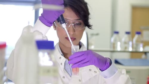 Focused Woman Scientist Pipetting Liquid in Medical Lab