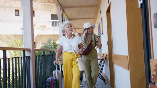 Amies âgées avec valises debout devant la chambre d'hôtel à l'extérieur