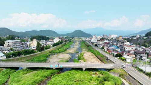 Aerial tracking shot over the Yomase river and the Yudanaka town, summer in Japan