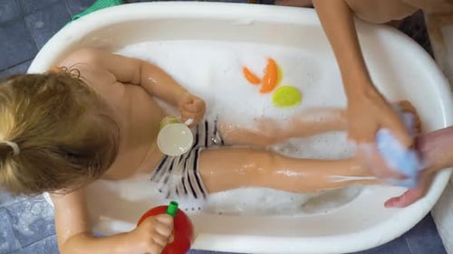 Child Enjoys Bath Time with Toys and Bubbles