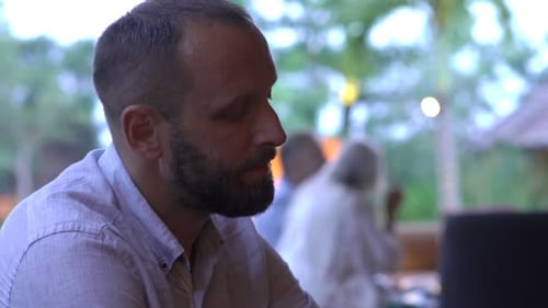 Handsome young man enjoys a refreshing cocktail in a beautiful garden cafe