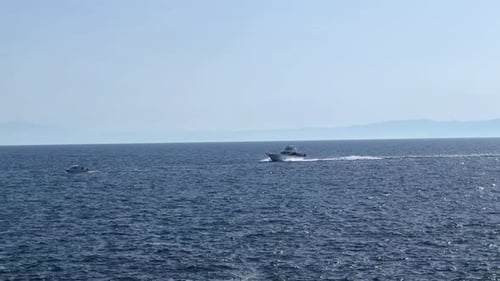 Boot, das an einem klaren Tag über das offene Meer mit der fernen Bergküste rast