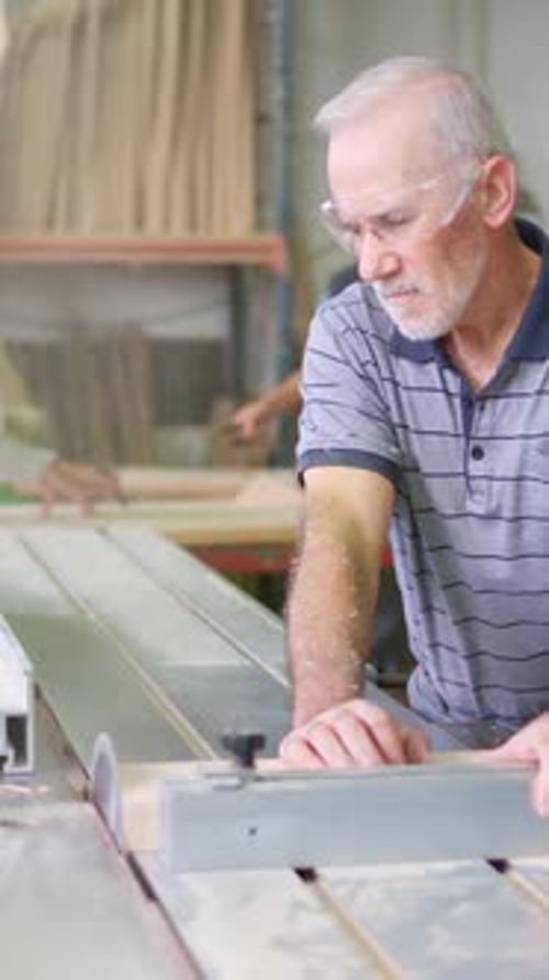 Senior Man Cuts Wood with Saw in Workshop