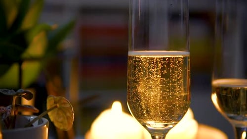 Close Up Of Golden Champagne In A Champagne Flute Glass With Bubbles Rising Against Blurry Candlelig