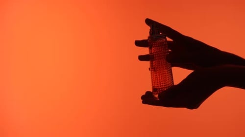 Silhouette of Hands Holding a Perfume Bottle