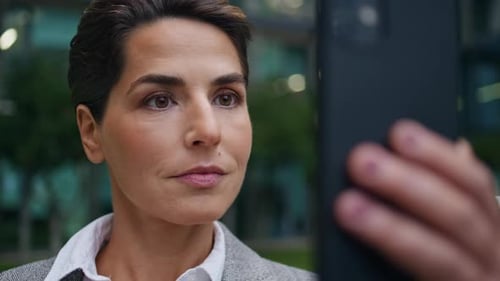 Businesswoman Video Chatting on Mobile Phone Outside Office