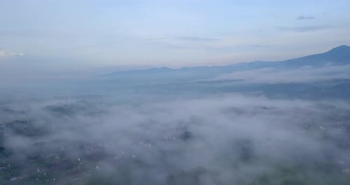 Drone footage of sea of fog above urban areas - Tropical city in Indonesia
