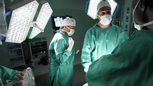 Diverse male and female surgeons operating on patient in operating theatre at hospital, slow motion