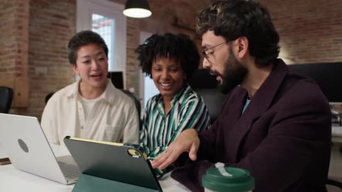 Enthusiastic Team Collaborating on Tablet in Office