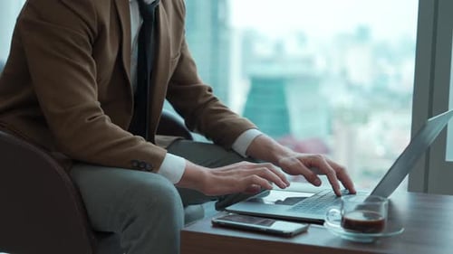 Businessman Typing on Laptop in Modern Office