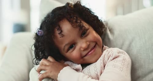 Child Hugs Stuffed Animal Smiling on Couch