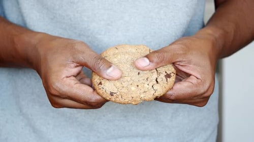Hands Breaking Chocolate Chip Cookie in Half