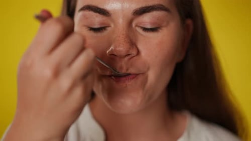 Woman Eating Spoonful of Food Close Up Studio Shot