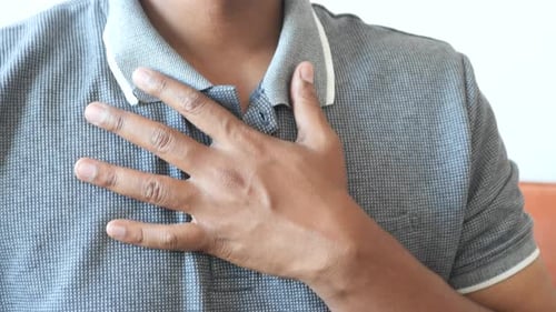 Young Man Suffering Pain in Heart and Holding Chest with Hand