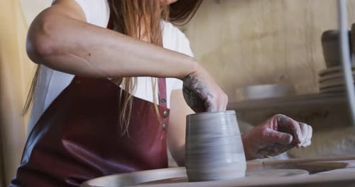 Creative caucasian woman works skillfully shaping clay in her pottery workshop