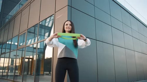 Woman Exercising with Resistance Band Near Modern Building